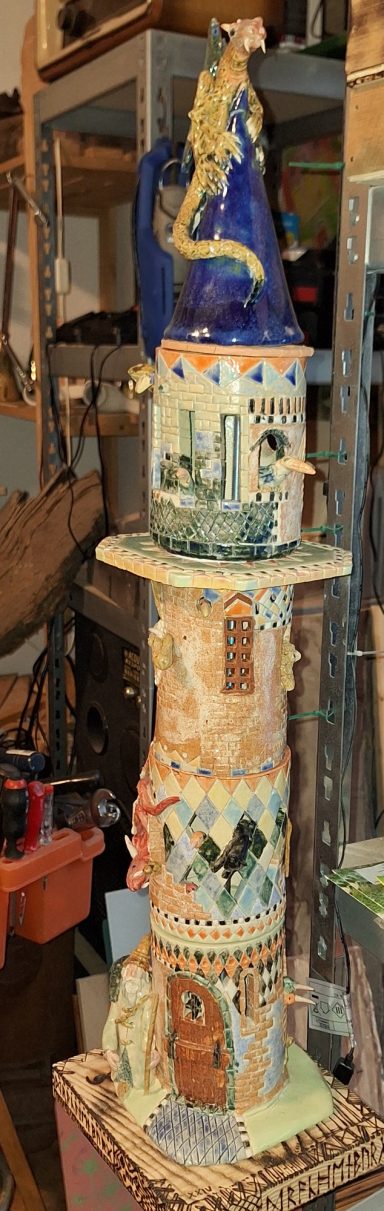 Bunte, kunstvoll bemalte Tonfiguren, übereinander gestapelt, mit verschiedenen Motiven.