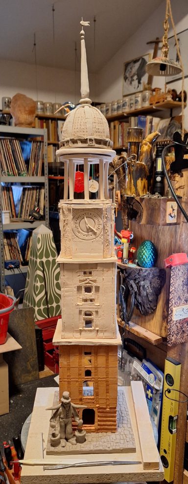 Keramikturm mit mehreren Etagen und einer spitzen Kuppel, umgeben von kreativen Materialien.